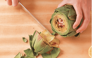 Trimming the top of an artichoke with a knife. 
