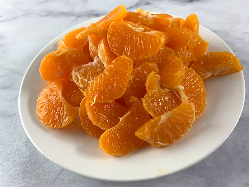 Sliced mandarin segments on a white plate. 