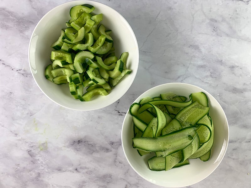 One white bowl with cucumber moons and the other with cucumber ribbons. 
