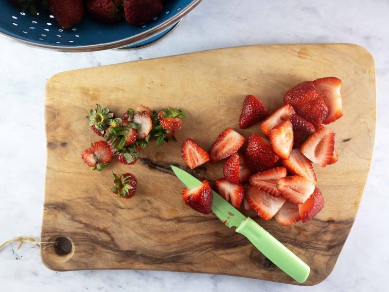 SLICING STRAWBERRIES ON A WOODEN BOARD