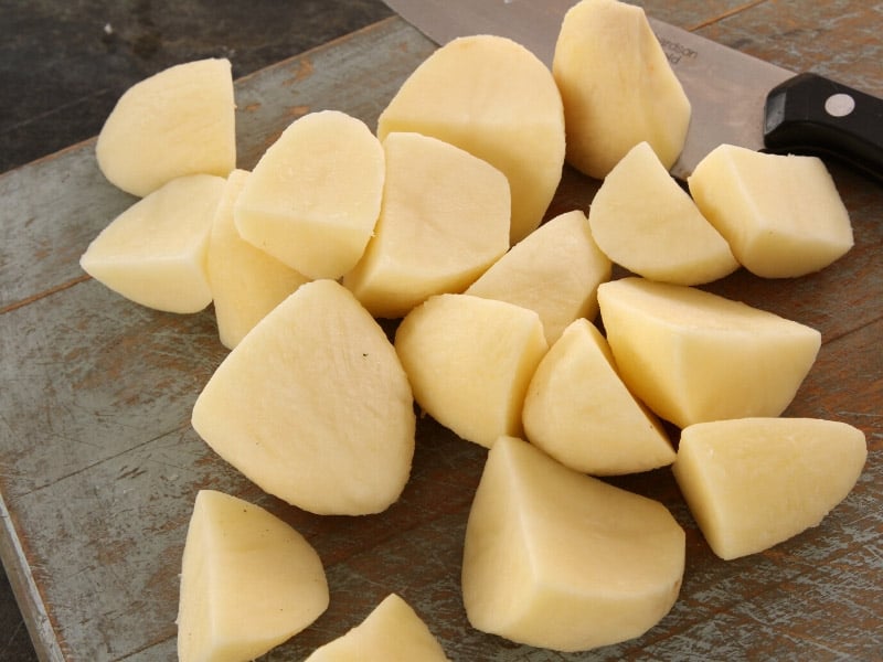 A close up of cut potatoes on a wooden board. 
