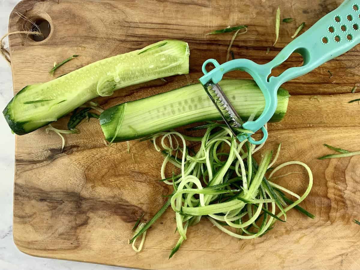 Cutting cucumbers into julienne with a peeler.