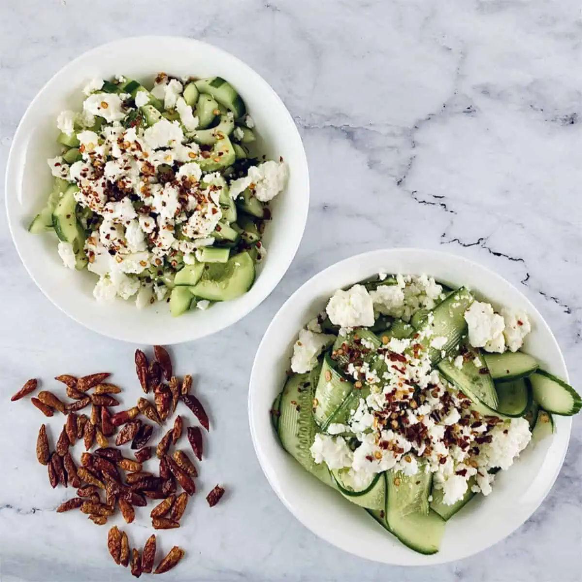 Two small white bowls with feta and cucumber salad. 