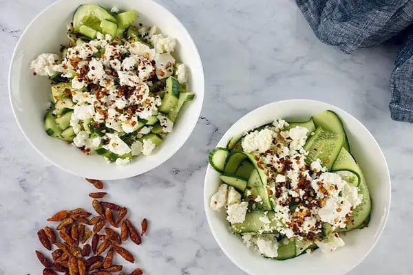 Cucumber feta salad cut 2 ways in 2 white bowls.