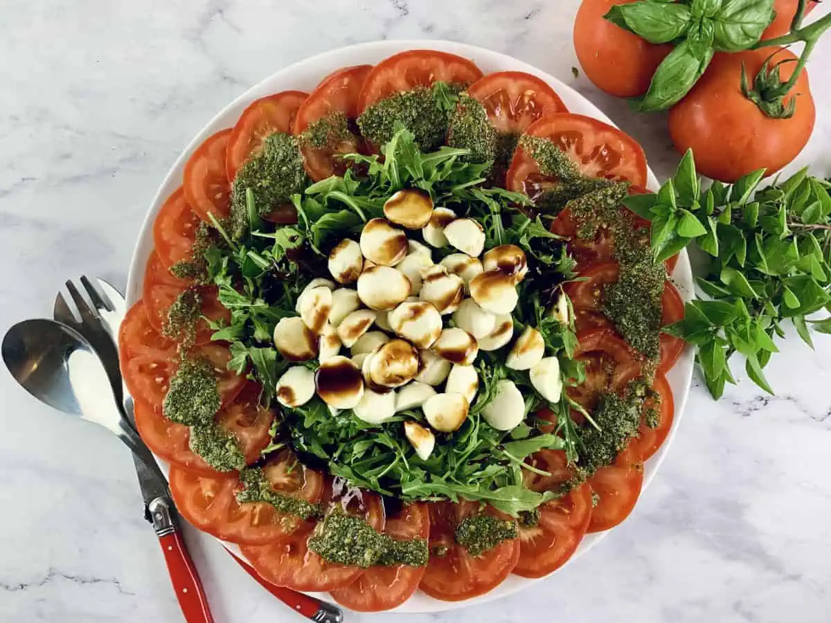 An aerial view of tomato mozzarella salad with rocket or arugula that has been drizzled with balsamic. 