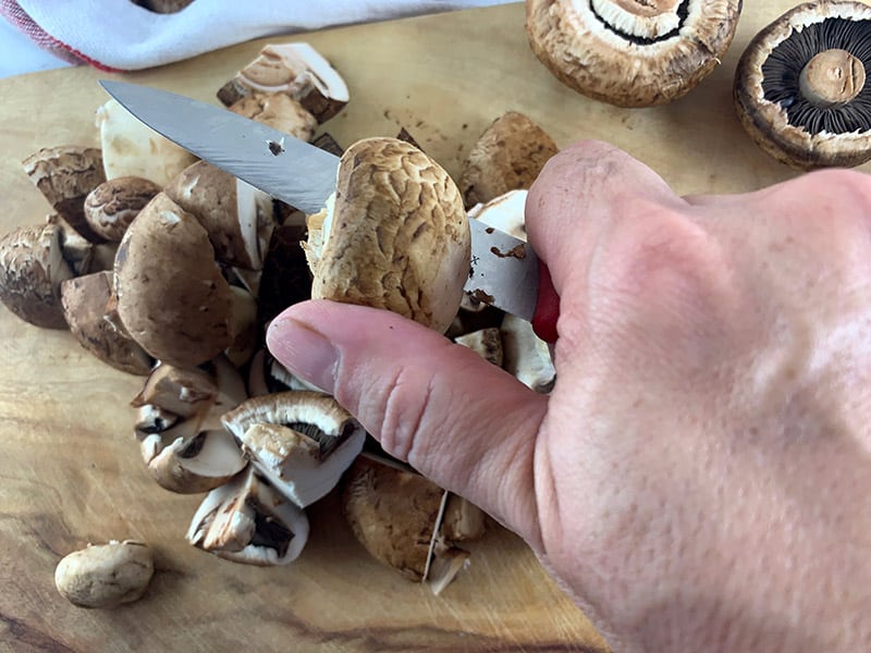 Slicing mushrooms on a wooden board. 