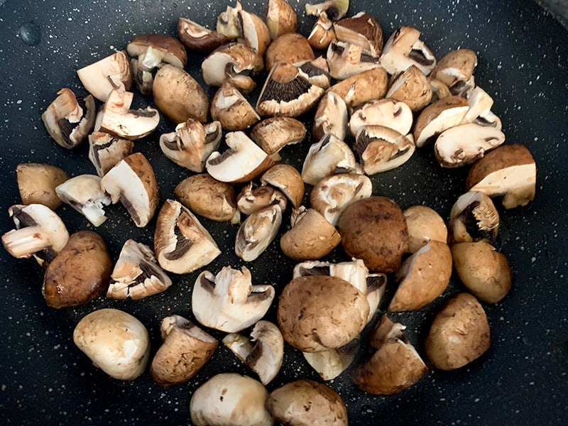 Mushrooms in a pan being satueed. 