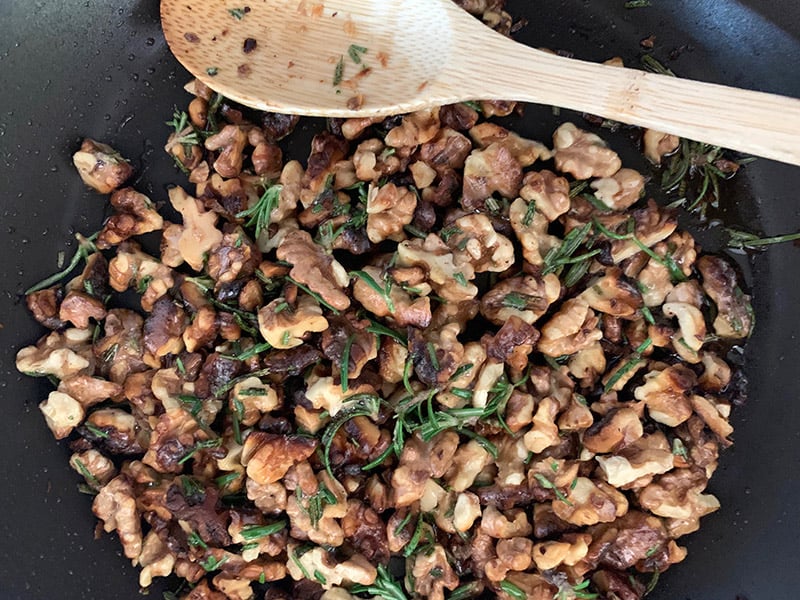 Stirring walnut and rosemary crumble in a pan. 