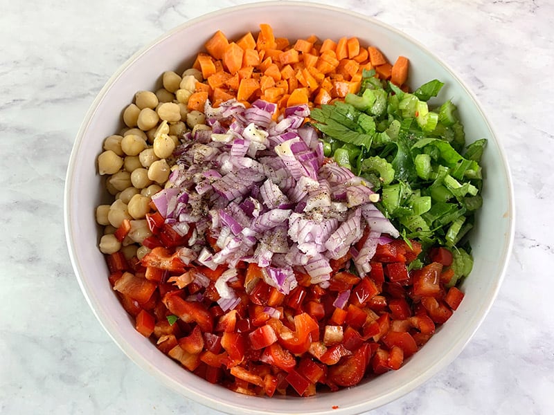 Prepared garbanzo or chickpea salad ingredients in a white bowl. 