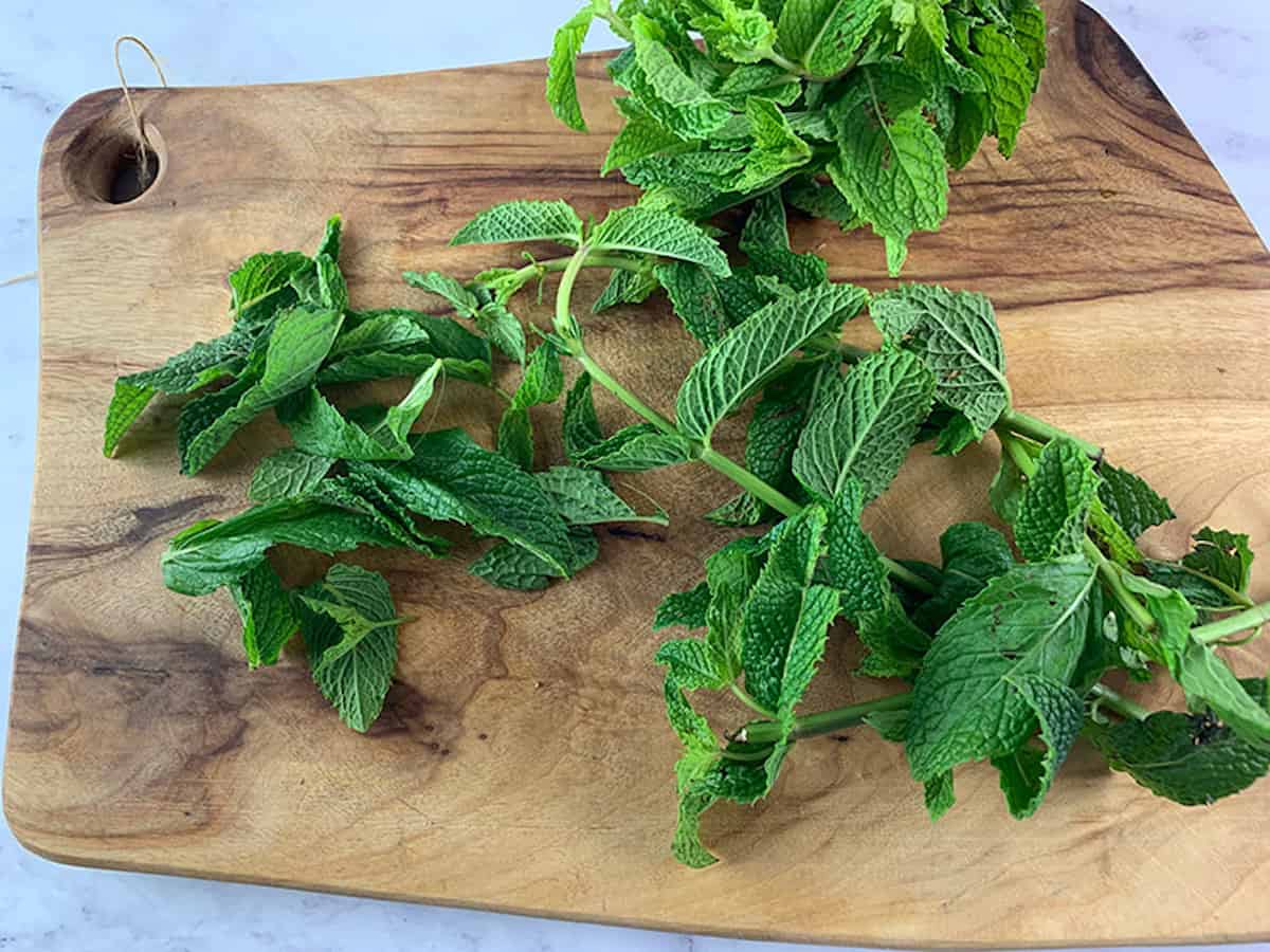 Stripping mint leaves from stems on a wooden board. 