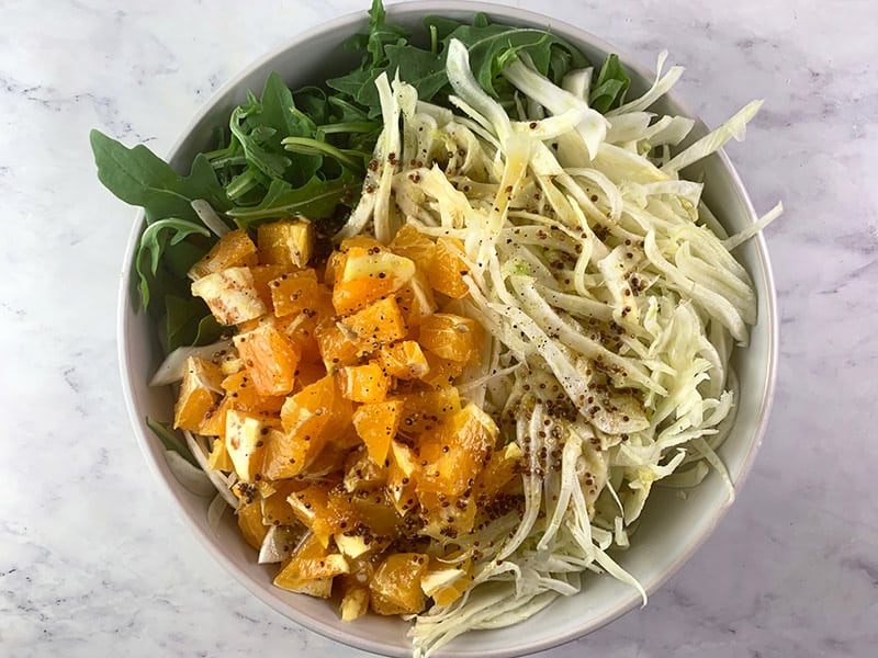 Prepared fennel and orange salad ingredients in a white bowl. 