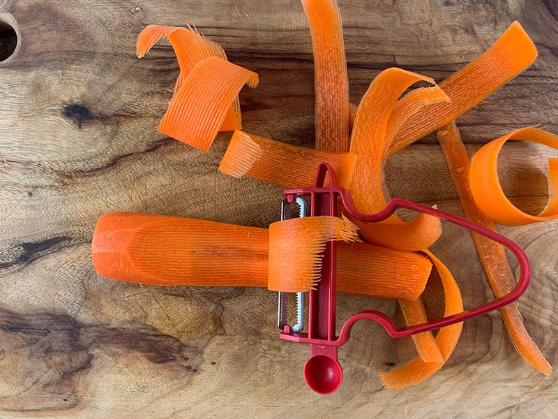 Aerial view of carrots of being cut into ribbons with a peeler. 