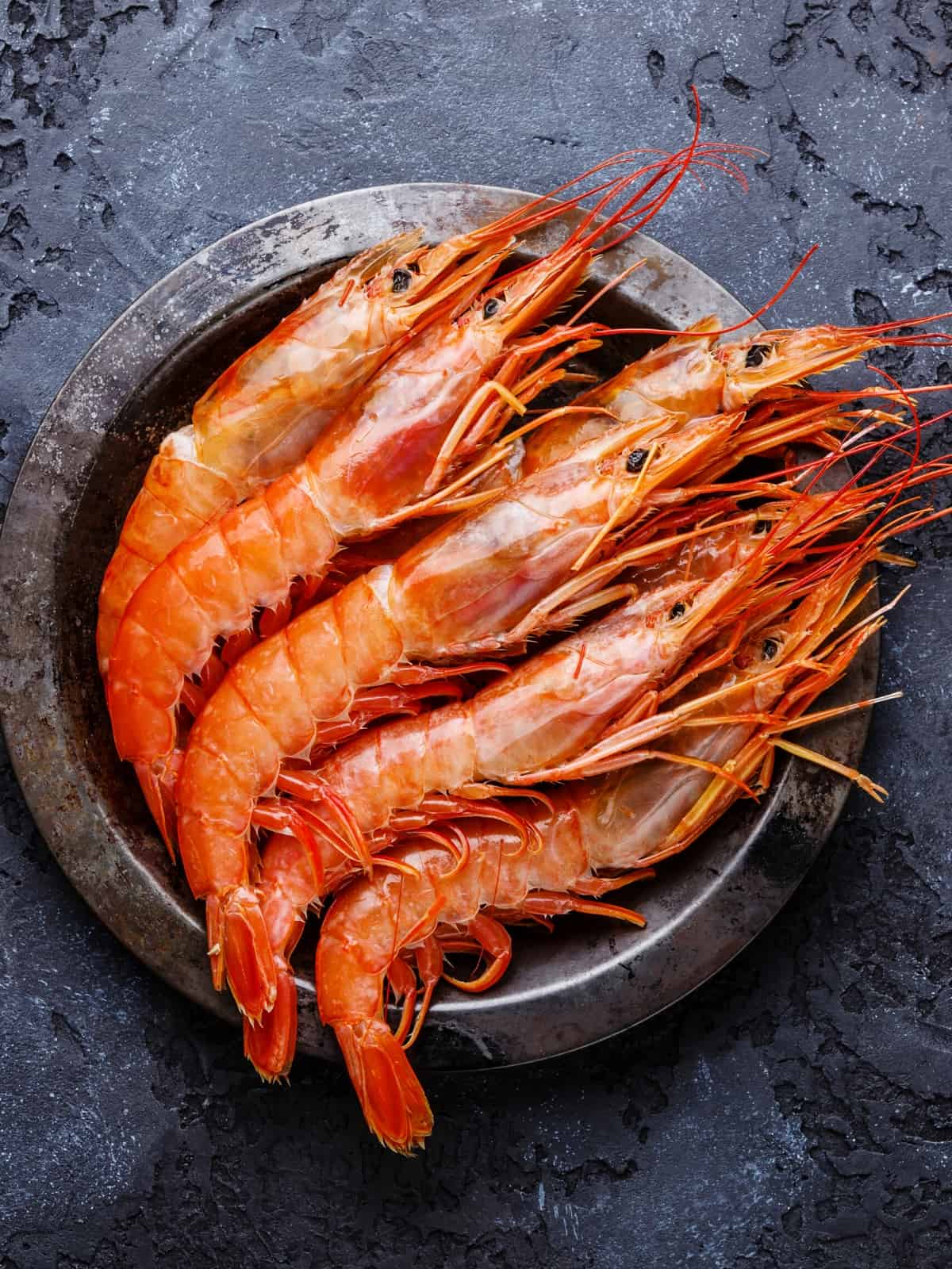 RAW FRESH PRAWNS ON A METAL PLATE ON DARK BACKGROUND