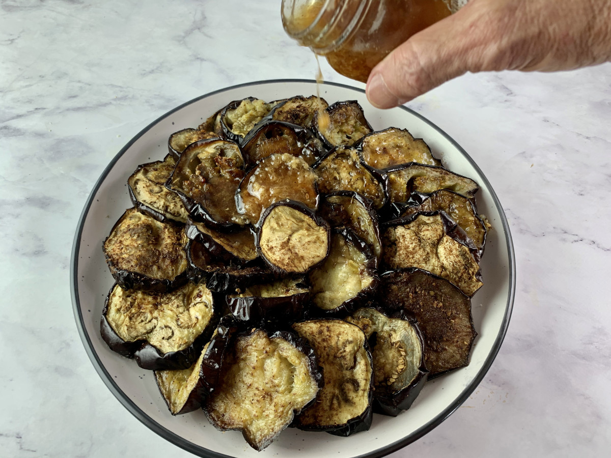 POURING VINAIGRETTE OVER ROASTED EGGPLANT ROUNDS