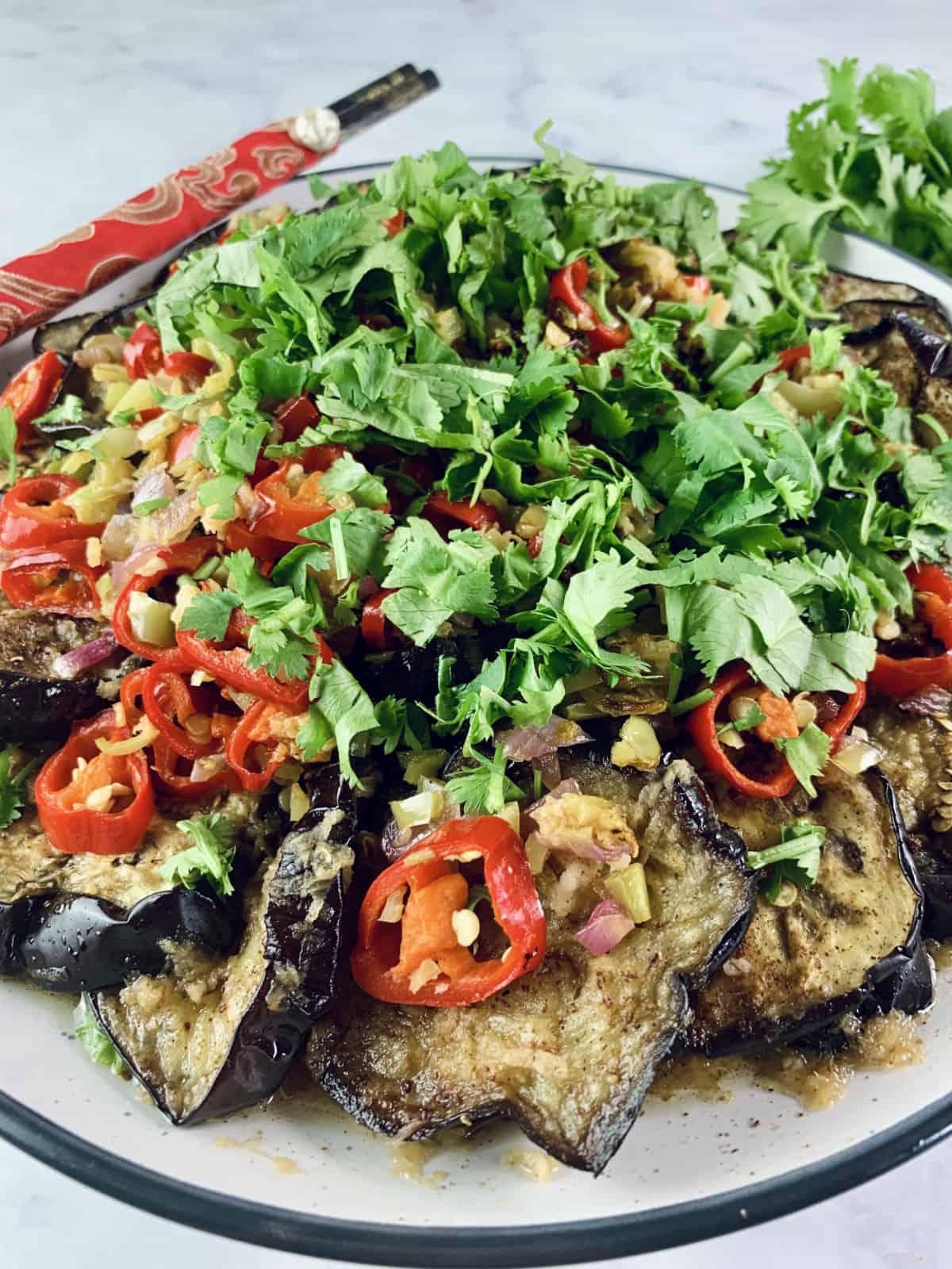 A Close-Up of a Chinese Eggplant Salad Portrait with red chopsticks and coriander on the side.