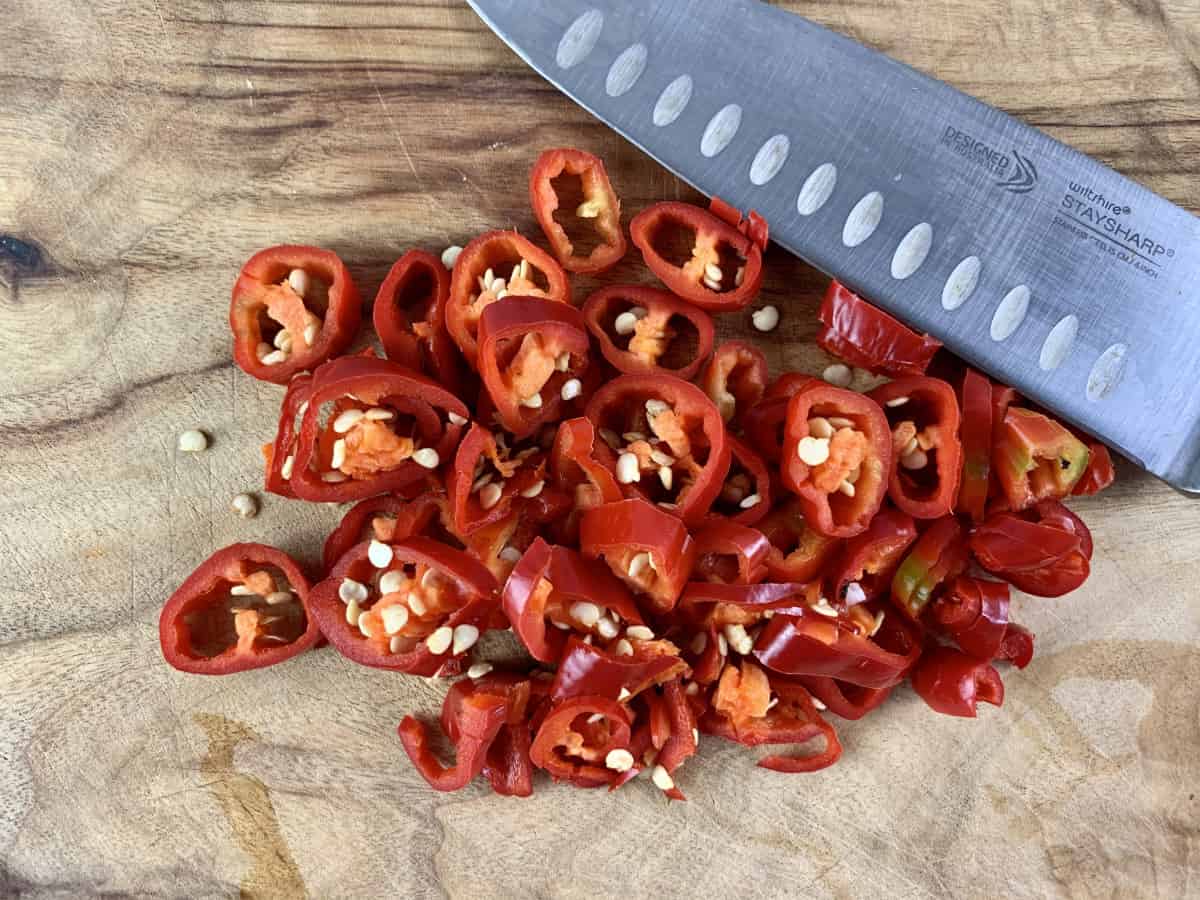 SLICING RED CHILLIES ON A BOARD WITH KNIFE