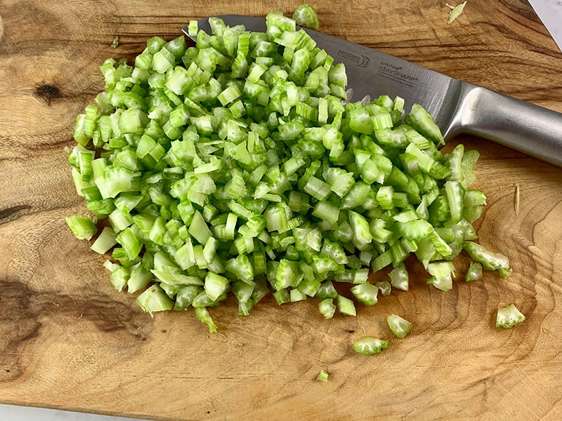 Dicing celery on wooden board with knife