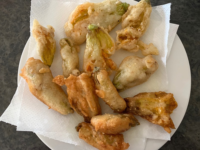 Fried zucchini flowers sitting on paper towels to drain. 