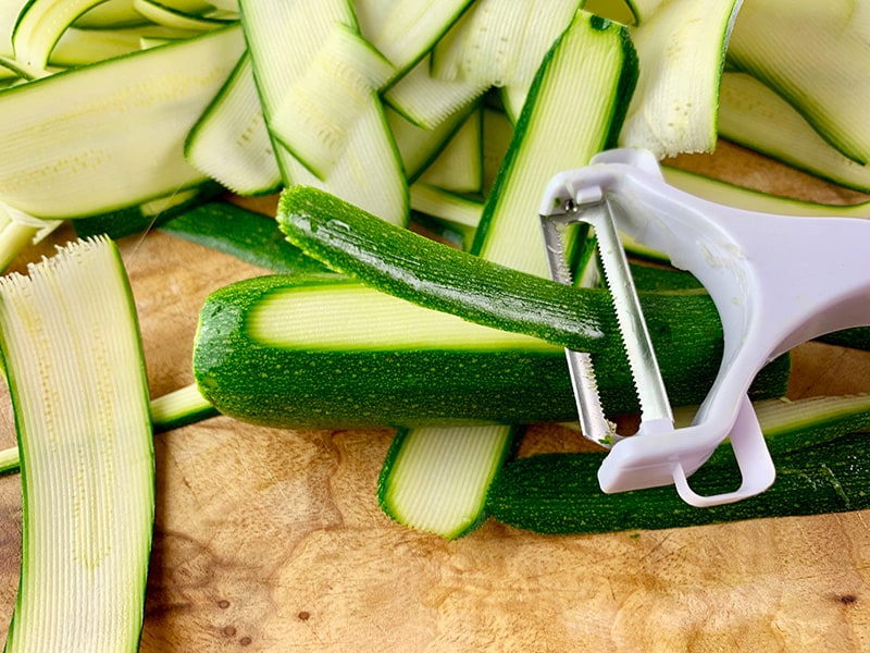 Cutting zucchini into ribbons with a peeler.