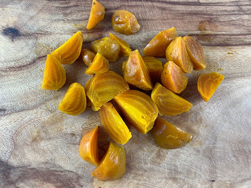 GOLDEN BEETS ON A WOODEN CHOPPING BOARD CHOPPED INTO WEDGES