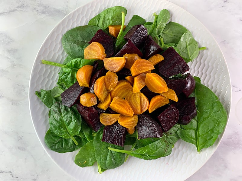 WASHED BABY SPINACH, RED BEETS & GOLDEN BEETS ON WHITE PLATE