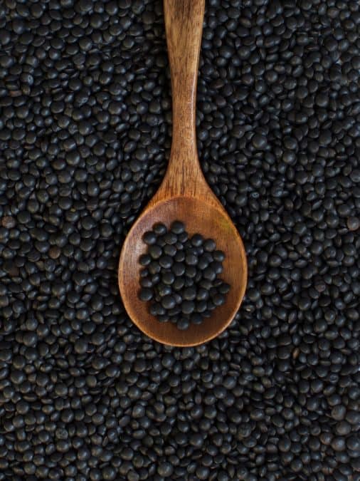 Black lentils with a wooden spoon.