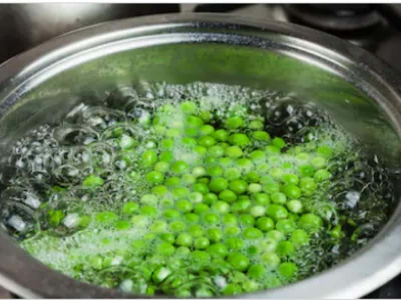PEAS BOILING IN A SAUCEPAN ON THE STOVE