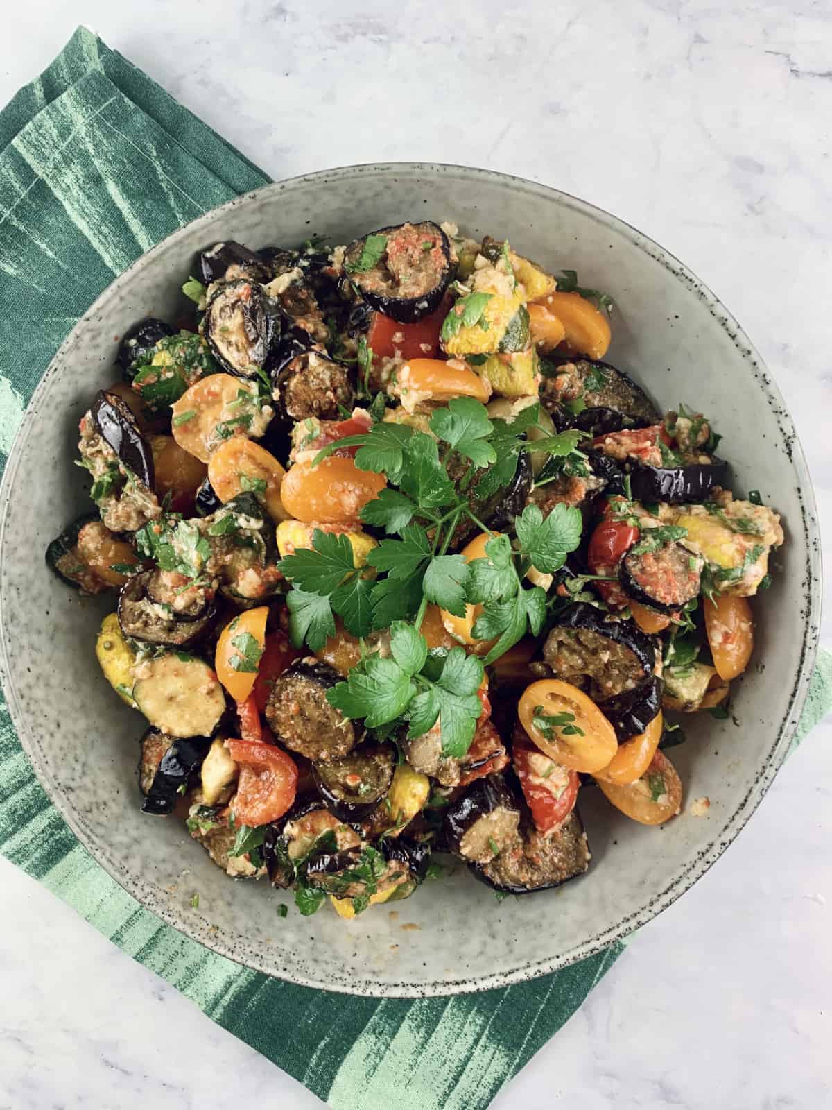 Summer Roasted Vegetable Salad in a ceramic bowl on top of a green tea towel.