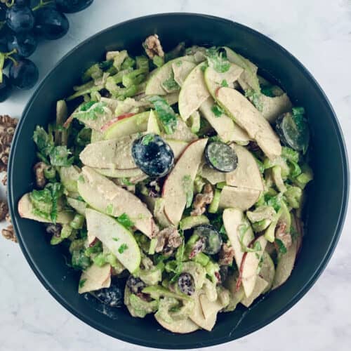 VEGAN WALDORF SALAD IN BOWL WITH WALNUTS AND GRAPES IN LANDSCAPE