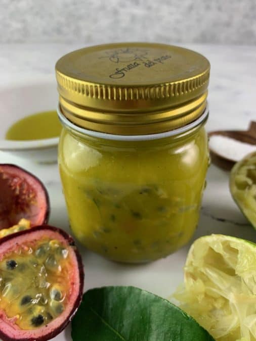 SHAKEN PASSION FRUIT DRESSING IN GLASS JAR WITH CUT PASSIONFRUIT, LIMES & LIME LEAVES