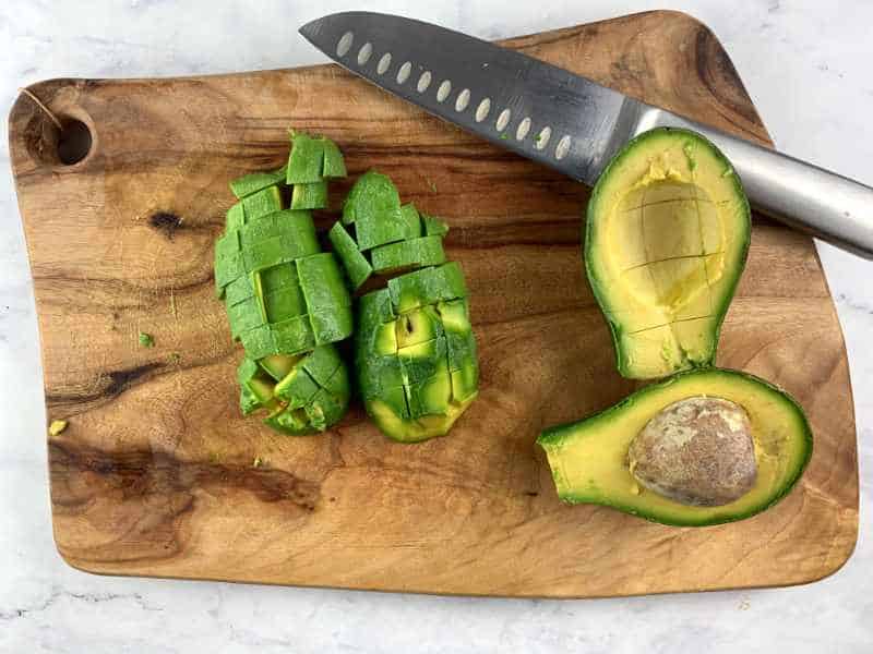 DICING SHEPHARD AVOCADOS ON WOODEN BOARD