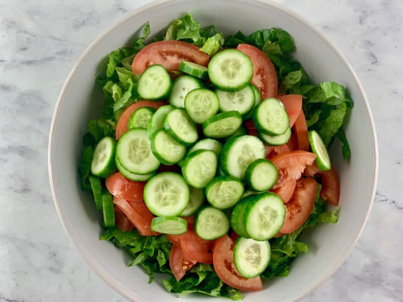 ADDING CUCUMBER ROUNDS TO SALAD BOWL