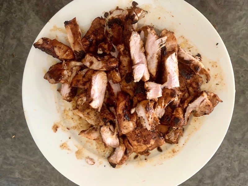 SLICED CHICKEN THIGH FILLETS ON WHITE PLATE
