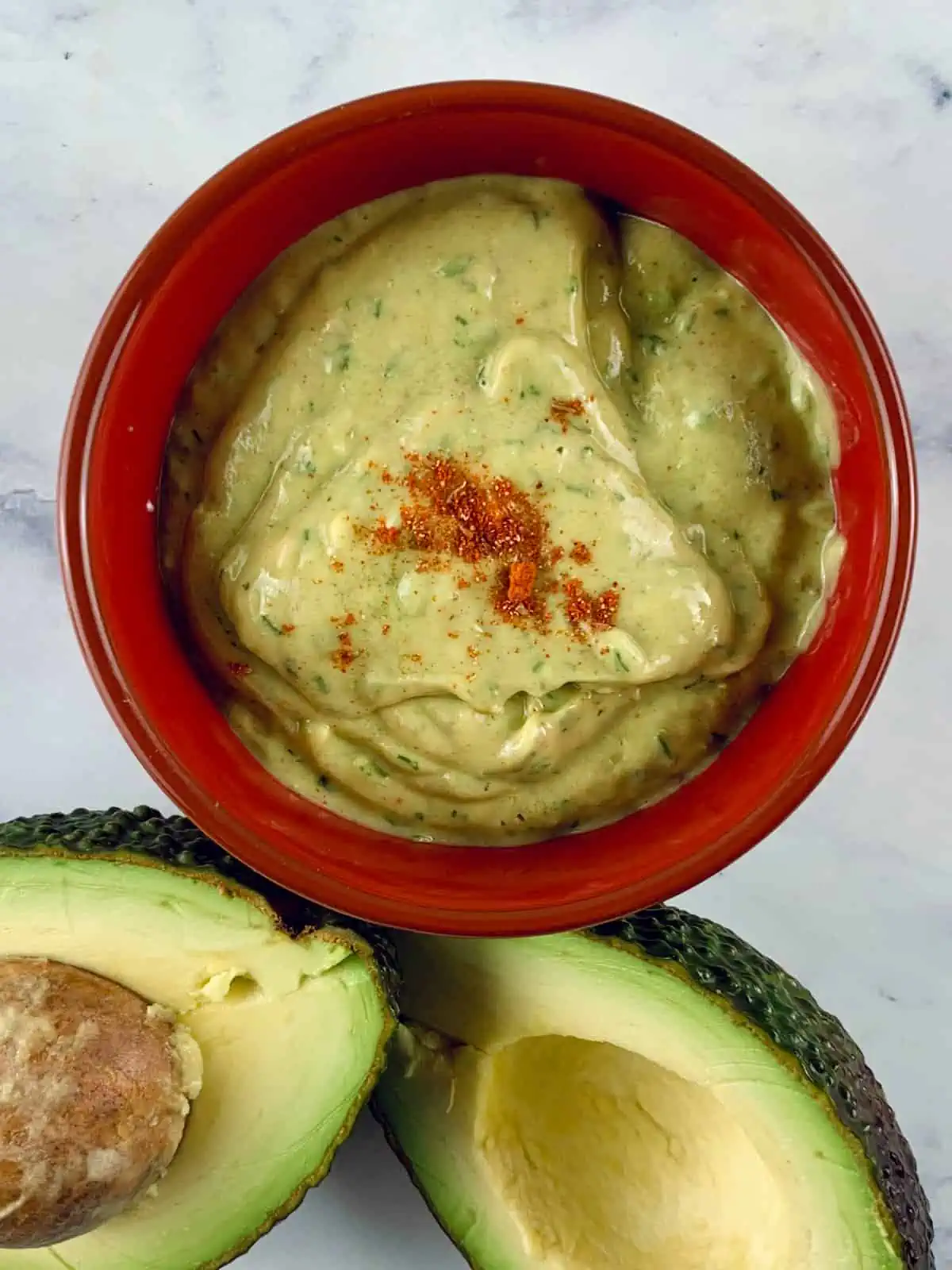 AVOCADO RANCH DRESSING IN RED BOWL WITH AVOCADOS ON THE SIDE