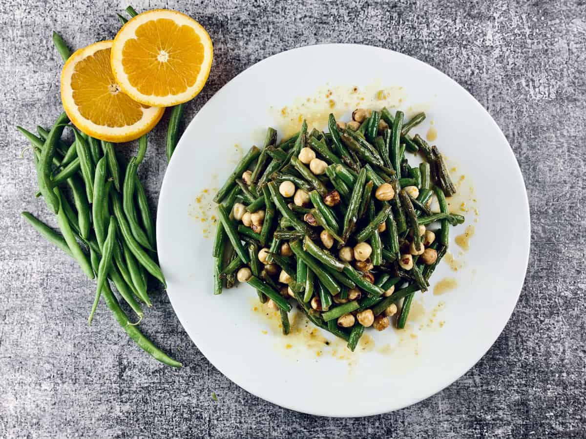 GREEN BEAN SALAD WITH ORANGE AND HAZELNUTS IN A WHITE PLATTER WITH ORANGE SLICES & BEANS ON THE SIDE