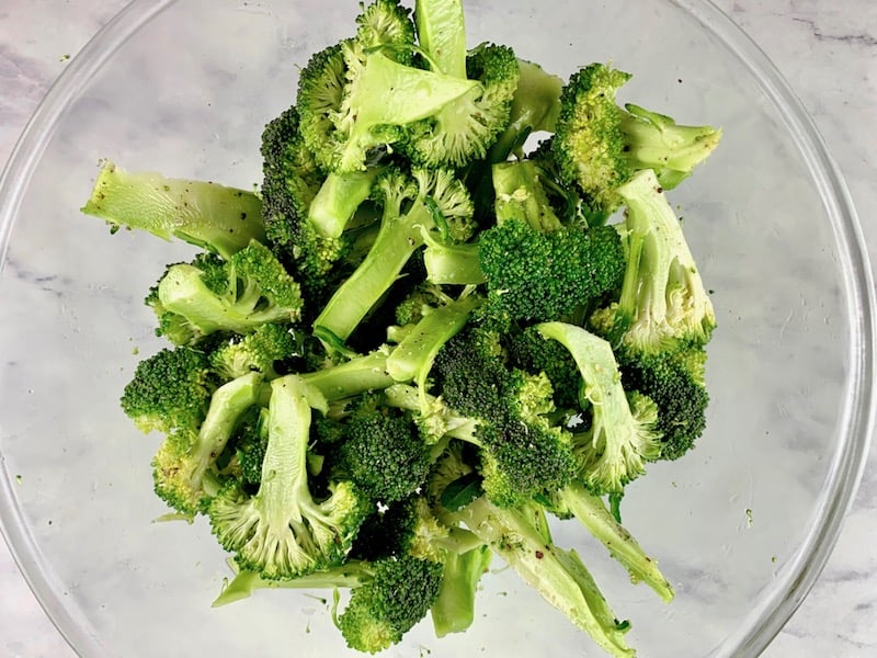 SLICED BROCCOLI FLORETS IN BOWL WITH OIL & SEASONING