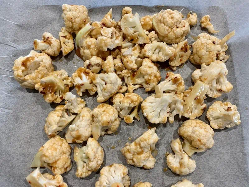 ADDING MARINATED CAULIFLOWER FLORETS TO A LINED BAKING TRAY