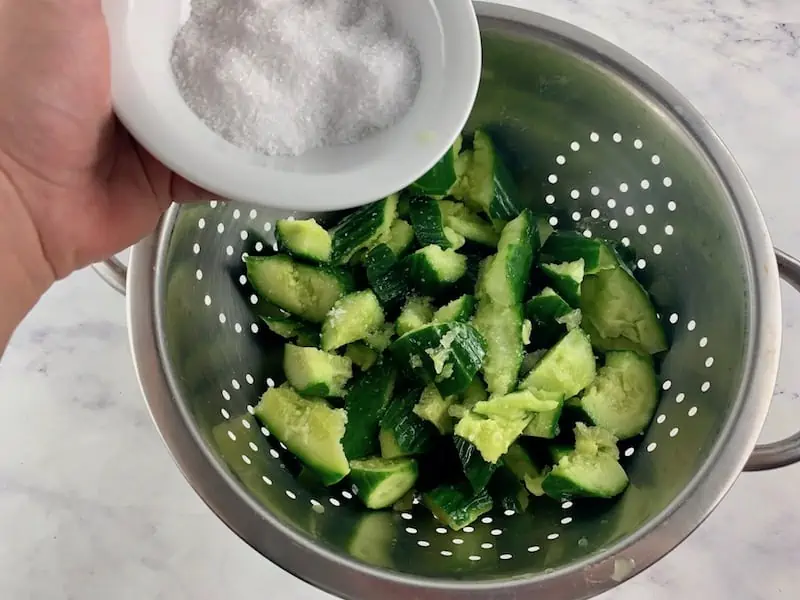 ADD SALT TO SMASHED CUCUMBERS IN A COLANDER