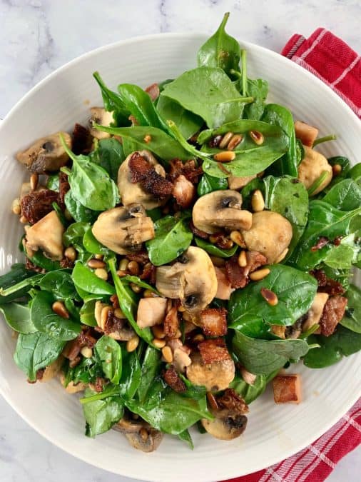 SPINACH MUSHROOM SALAD PORT IN WHITE BOWL WITH RED TEA TOWEL