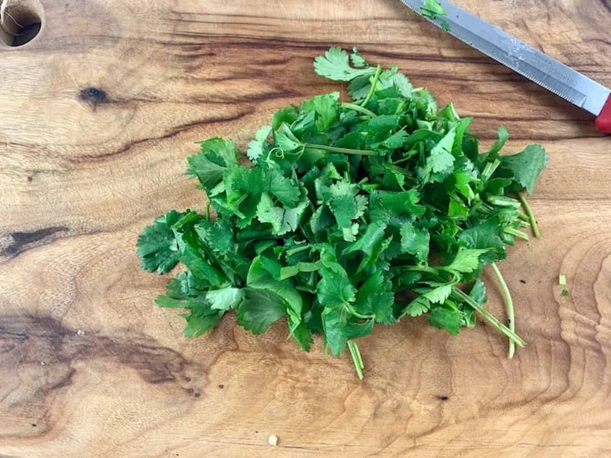 CHOPPED CORIANDER ON WOODEN BOARD WITH KNIFE