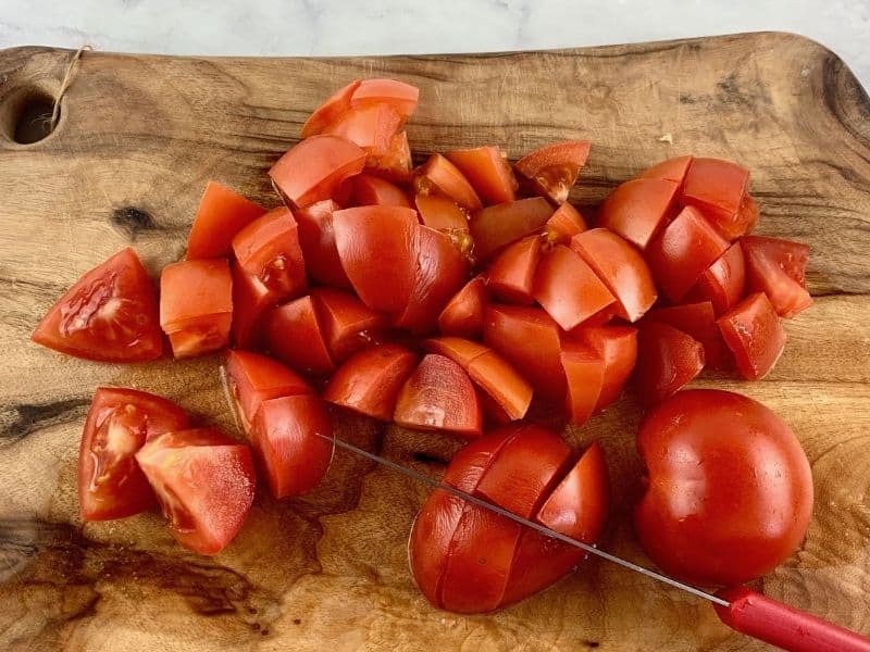 DICING TOMATOES ON A WOODEN BOARD WITH A KNIFE