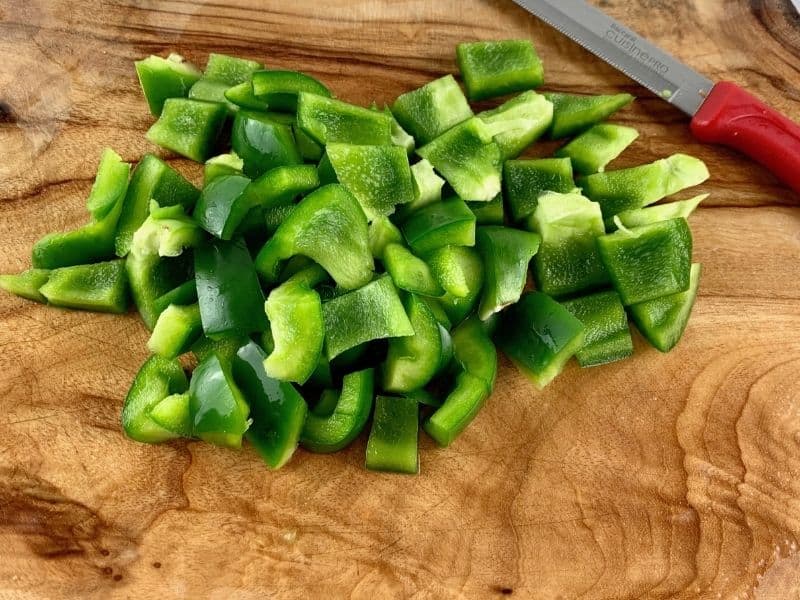 DICING PEPPERS ON A WOODEN BOARD WITH A KNIFE