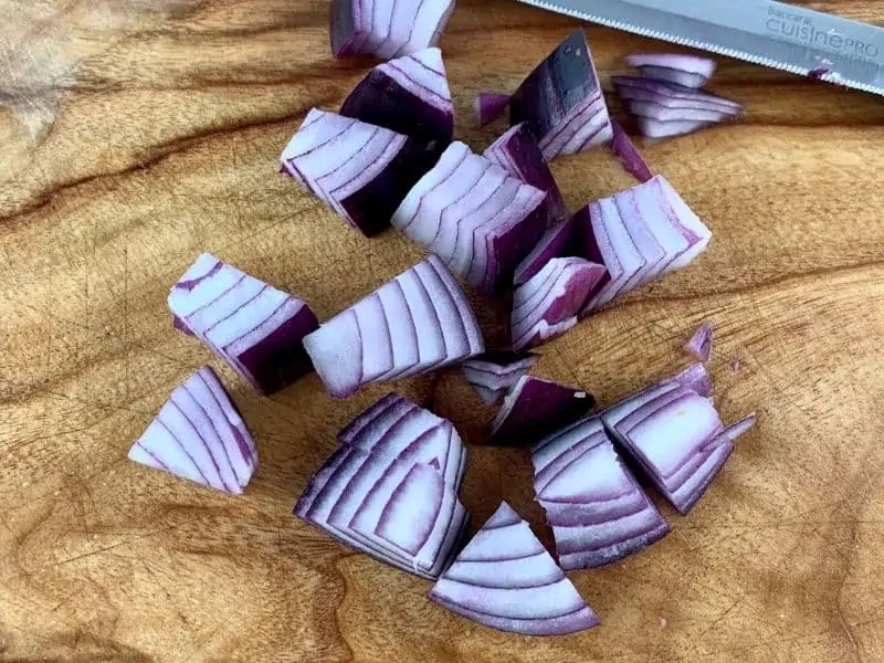 DICING RED ONION ON A WOODEN BOARD WITH A KNIFE