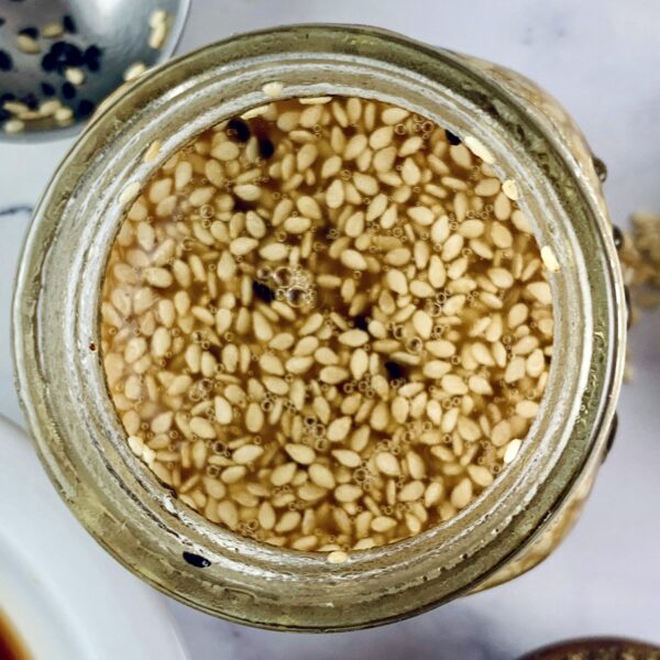 Overhead view of sesame vinaigrette in a glass jar with ingredients around.