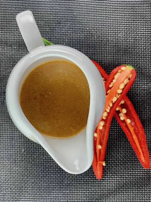 HARISSA VINAIGRETTE IN A WHITE JUG WITH CUT CHILLIS ON THE SIDE