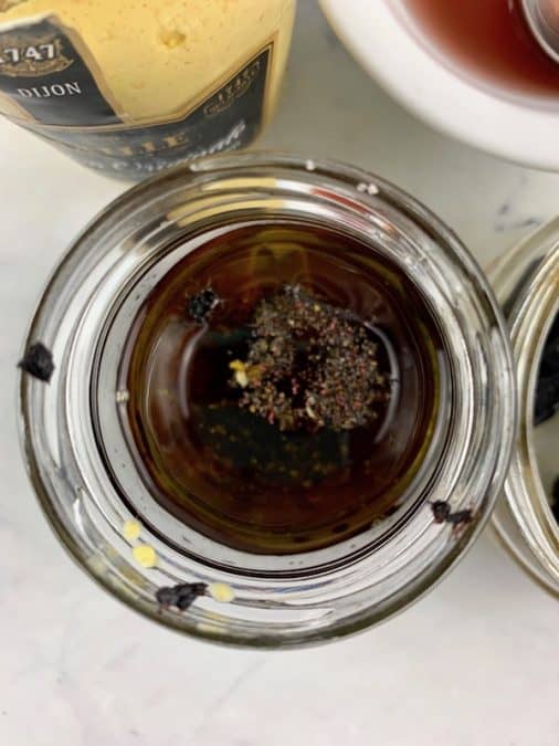 BLACK GARLIC VINAIGRETTE INGREDIENTS IN GLASS JAR WITH INGREDIENTS SCATTERED AROUND