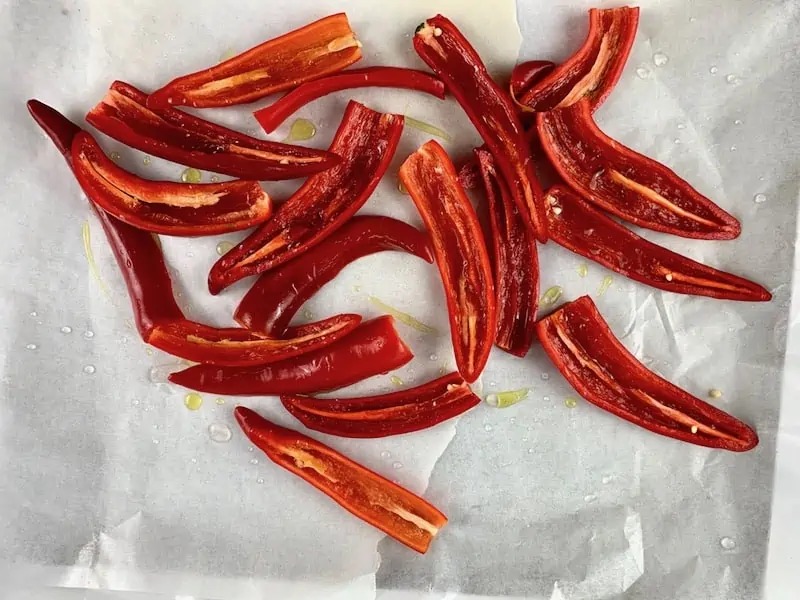 HALVED RED CHILLIS ON A BAKING TRAY WITH OIL & SALT