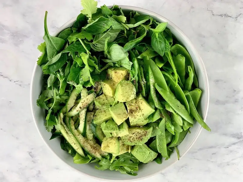 Prepared ingredients in a bowl to make spinach arugula salad.