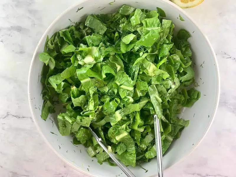 TOSSING MAROULOSALATA IN A WHITE BOWL TO COMBINE