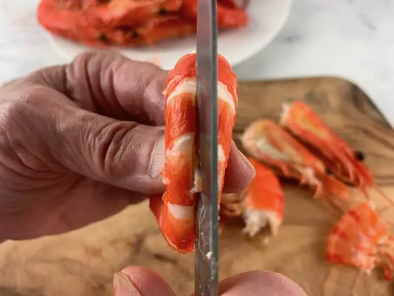 hands slitting the back of a cleaned prawn with a knife